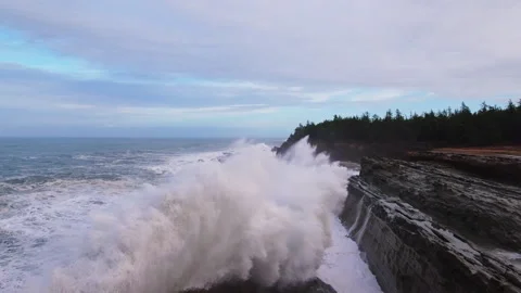 Aerial Forward Shot Of Waves Splashing On Rocky Coastline Against Cloudy Sky - Stock Footage 250486185