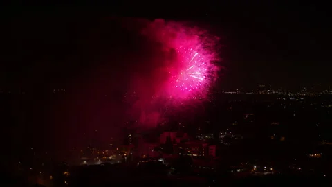 Aerial Forward Sparks Of Exploding Fireworks At Night In City - Los Angeles, Stock Footage 169489989
