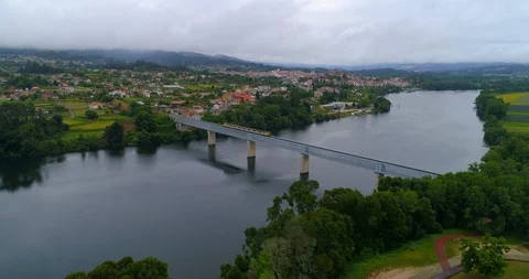 Aerial Forward of Train Passing Short Bridge Over the Water in Valenca Portugal Stock Footage 113939631