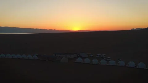 Aerial forward view of traditional nomad yurt camp lined up on alpine steppe at Stock Footage 346505051