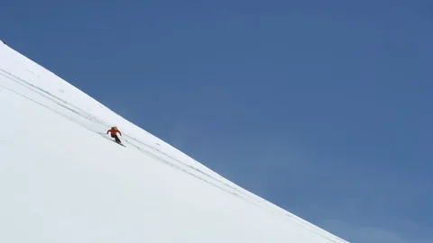 Aerial of freeride skiing down big mountain with blue sky horizon Видео 124227559