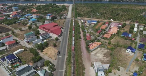 Aerial: freight train crosses a town intersection near a vast palm plantation Stock Footage 334909288