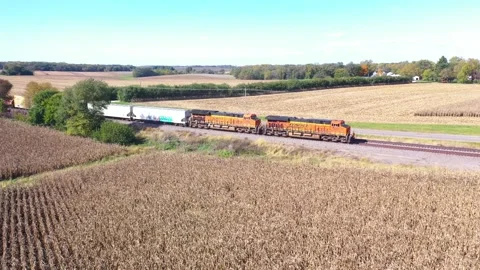 Aerial of a freight train passing through cornfields in the Midwest. Video stock 164449407