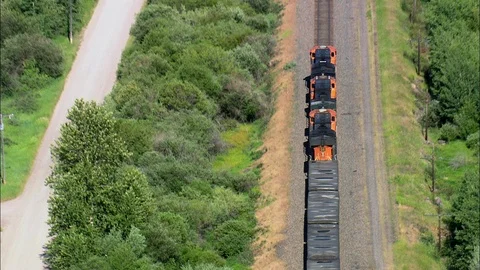 Aerial of freight train running on track through green field, Following train Stock Footage 109469164