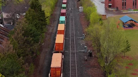 Aerial freight train transporting containers on railway tracks through suburbs s Stock Footage 334697049