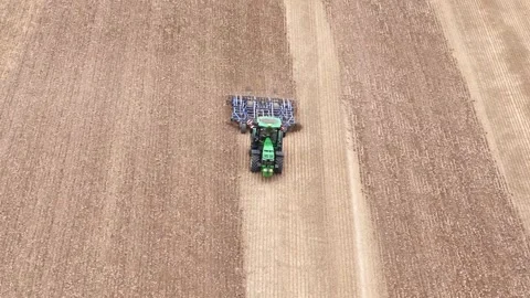 Aerial frontal pullback over Etchilhampton fields, showcasing a tractor Stock-Footage 286109677
