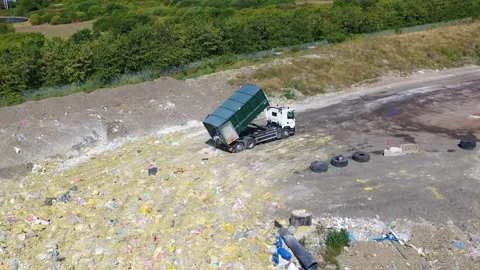 Aerial of garbage truck unloading a container full of garbage on a junkyard Stock Footage 298649754