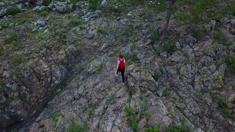 Aerial. girl tourist with a backpack sneaking through the rocky terrain. Altai Stock Footage