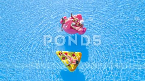 AERIAL Girls and a boy lying on fun colorful floaties in pool on summer vacation Stock Photos