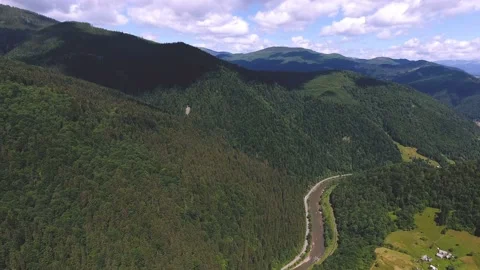 Aerial of a gleaming river and a tiny community in the Carpathians in summer Stock Footage 89922052