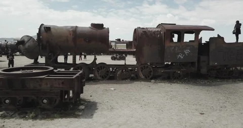Aerial glides alongside the side of a line of abandoned rusty trains in Uyuni Video stock 87479872