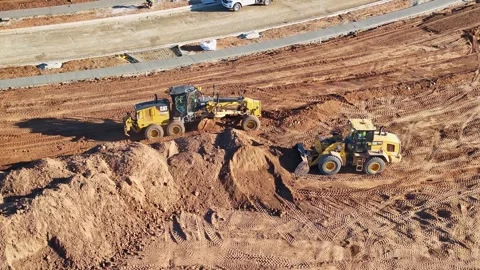 Aerial of a grader and front end loader moving dirt around a building site Stock Footage 278340236