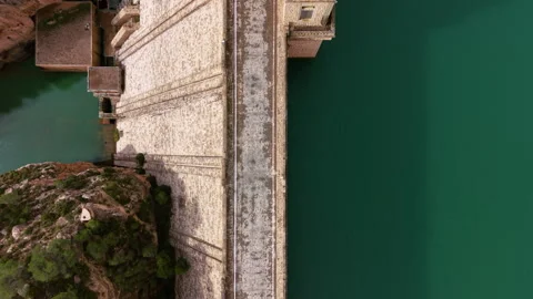 Aerial of a gravity dam showing crest roadway, upstream reservoir interface and 動画素材 332894089