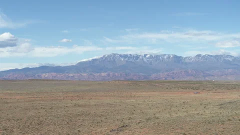 Aerial of green fields below snow capped mountains in southern Utah Stock Footage 268736339