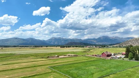 Aerial Green Fields Red Barn and Mountain Landscape Jackson Wyoming Flyover Stock Footage 339817260