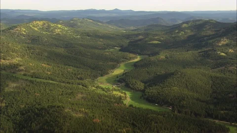 Aerial of green path through grass covered mountain ranges, Black Hills National Stock Footage 109450536
