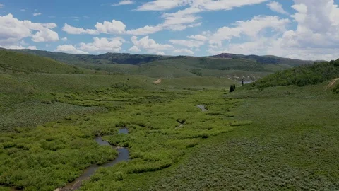 Aerial-Green valley small stream gravel road to high mountain Lake-POV Video stock 112363755