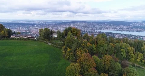 Aerial green view of trees and farm with fall colors revealing city of Zurich Stock Footage 80878053
