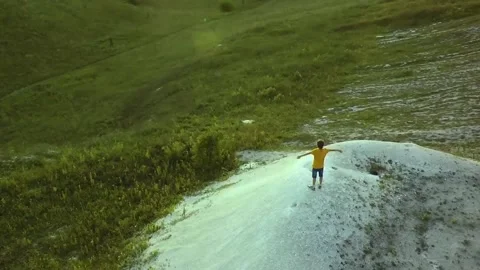 AERIAL:  guy standing on the mountain stretching his hands feel freedom and t Video stock 88704637