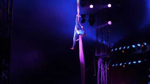 An aerial gymnast performs tricks on the fabric under the dome of the circus. Stock Footage 313470883