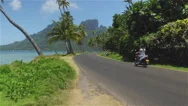 Aerial: Happy Female Motor Biking Down The Bora Bora Road Stock Footage