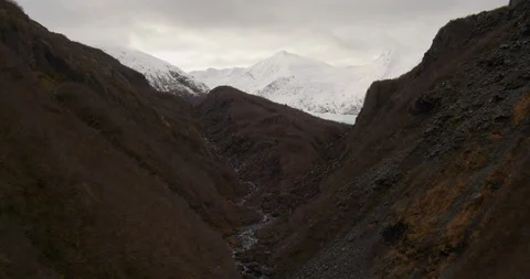 Aerial helicopter flyover through sparsely wooded hills, towards mountains, Stock Footage 108434863