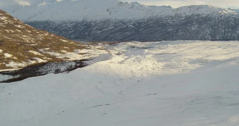 Aerial helicopter shot, pushing around corner of mountainside across rippling Stock Footage 115106989