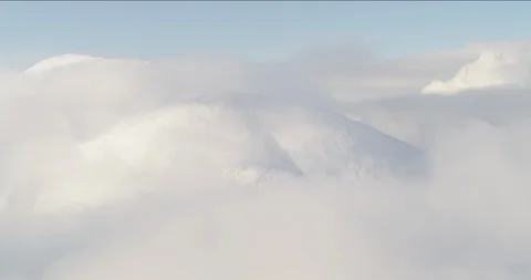 Aerial helicopter shot through clouds and over snowy mountain peak, reveals more Stock Footage 115097503