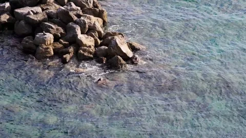 Aerial High Angle Shot of Blue Ocean Water Rippling Against Rocky Shore Stock Footage 331710634