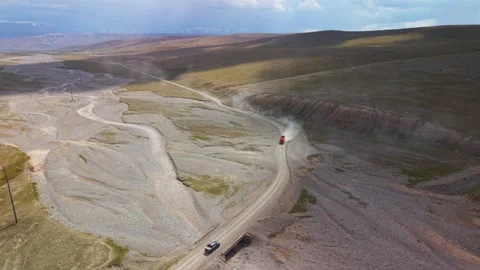 Aerial high-angle shot of pickup truck following dump truck kicking up dust Stock Footage 346505208