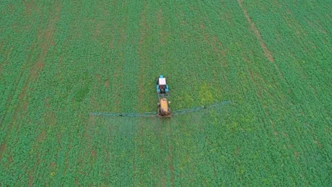 Aerial high angle shot of a tractor machine spraying the field with pesticides Stock Footage 197059534