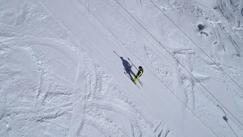 Aerial - High angle tracking shot of skier being pulled up by anchor ski lift Stock Footage 83999522