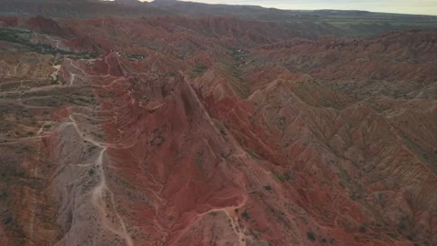 Aerial high-angle view over labyrinth of eroded red rock ridges and clay Stock Footage 346376564