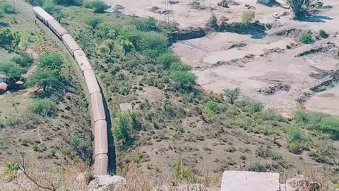 Aerial high angle view of passenger train navigating mountain valley 库存影片 333542747