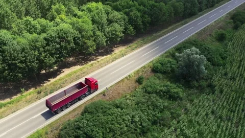 Aerial high-angle view of a red dump truck driving along a paved asphalt co.. Stockbeeldmateriaal 341492523