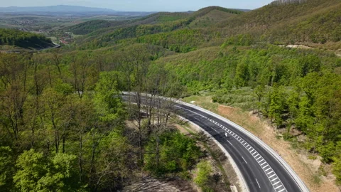 An aerial high-angle view shows a modern asphalt highway winding through a Vídeos de archivo 334171817