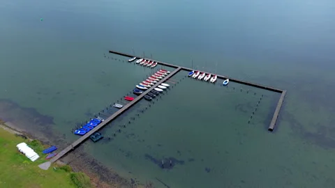 Aerial high angle view of small sailboats and colorful dinghies moored Stock Footage 340105370
