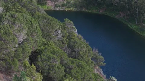 Aerial high angle view of a tranquil blue lake surrounded by forest Stock Footage 339377494