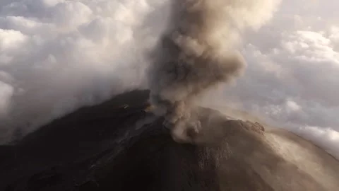 Aerial High Angle of Volcanic Ash Plume Bursting from Crater Above Clouds Video stock 322182940