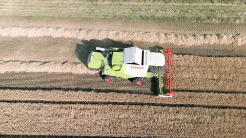 Aerial high level tracking view clip of a combine harvester harvesting wheat Stock Footage 205330700