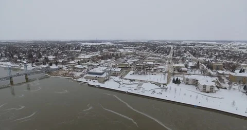 Aerial high push over river towards small town in winter Stock Footage 86297387