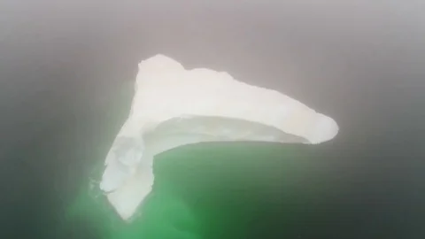 Aerial high shot of large iceberg in cold arctic waters in fog Stock Footage