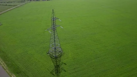 AERIAL High-voltage tower summer blue sky background green grass orbit circle Video stock 78677135
