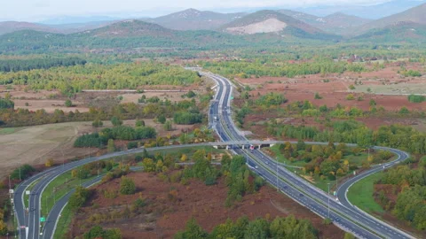 AERIAL: Highway interchange surrounded by fields and colorful autumn woodland Stock Footage 341179367