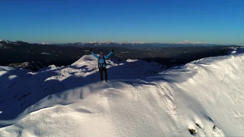 Aerial - Hiker in mountain wear standing on top of mountain in worship pose Stock Footage