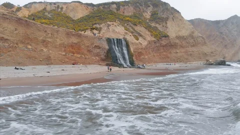 Aerial: Hikers & Waterfall going into the ocean water in California, USA Stock Footage