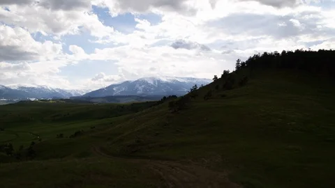 Aerial of hilly landscape under cloudy sky with view of mountains Stock Footage 124225857