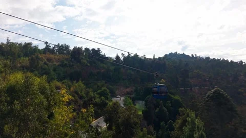 Aerial Horizontal Tracking Shot of Blue and Red Cable Cars Passing Over a F.. Video stock 339254136