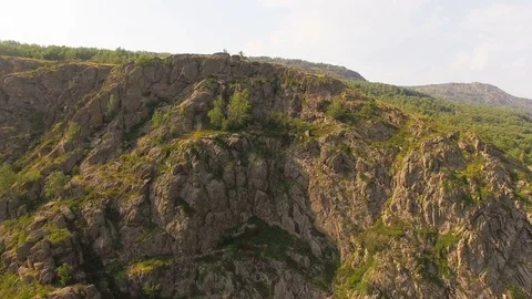 AERIAL: A huge cliff covered with trees during sunset among lovely landscape Video stock 78031985