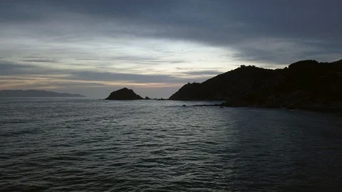 Aerial Hyper Lapse Cloudy Sunset over rock coast with island in background Stock Footage 89323048